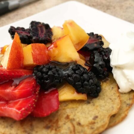 close up of pancakes topped with warm, syrupy fruit