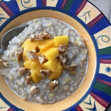 Banana date porridge topped with mango and nuts