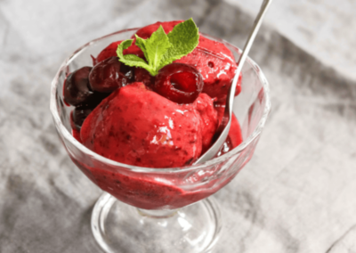 Cherry sorbet in a serving glass, topped with cherries and mint
