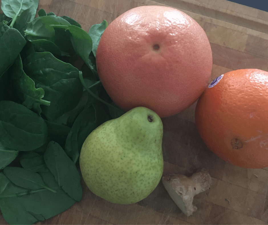 Spinach, grapefruit, orange, pear and ginger on a chopping board