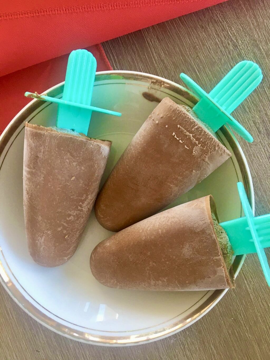 3 choc banana popsicles laying on a saucer