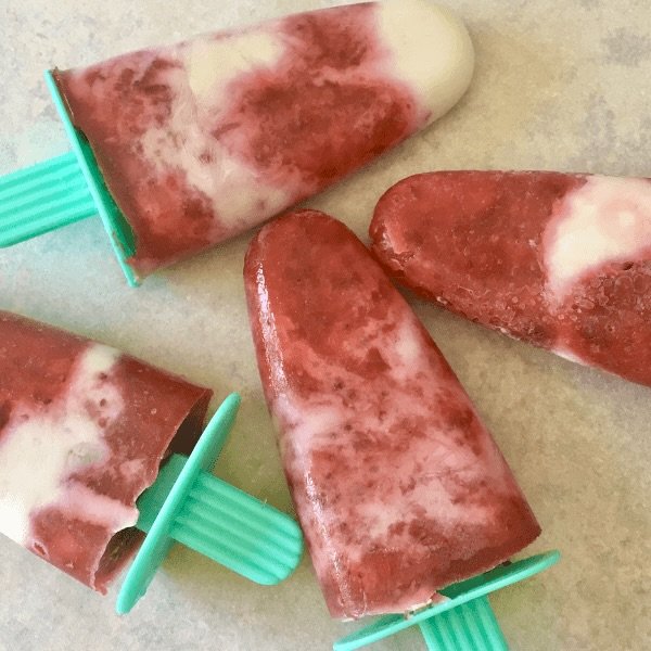 strawberries and cream popsicles laying on a bench