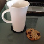 cup of tea and a choc chip cookie next to a computer