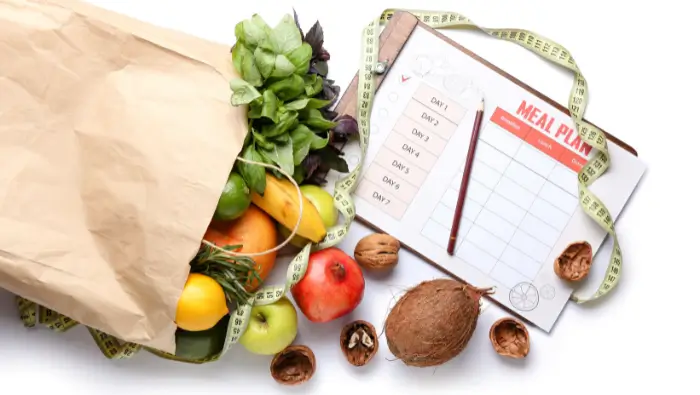 Bag of fruit & veg on a table next to a meal planner