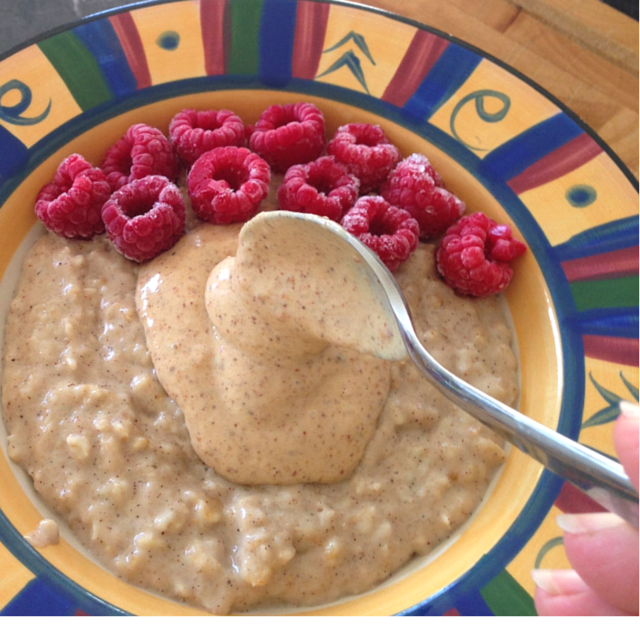 Coconut milk porridge topped with raspberries and almond butter