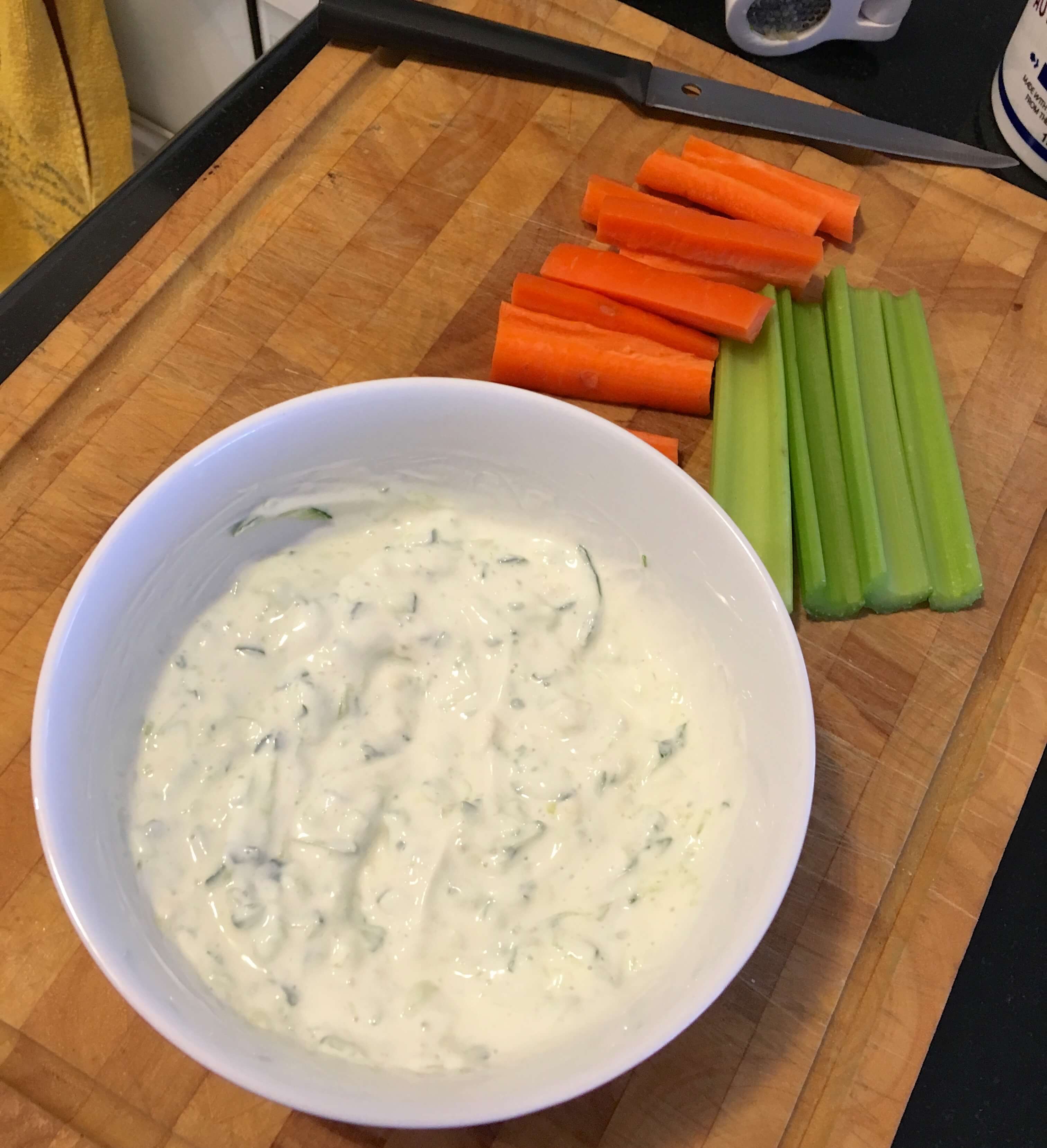 tzatziki dip in a bowl with carrot and celery sticks