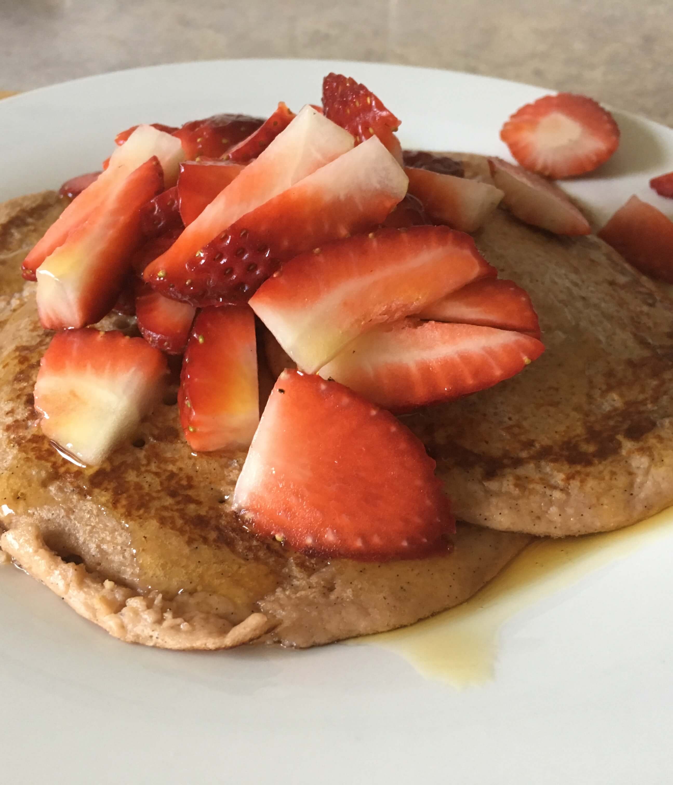 pancakes topped with strawberries and maple syrup