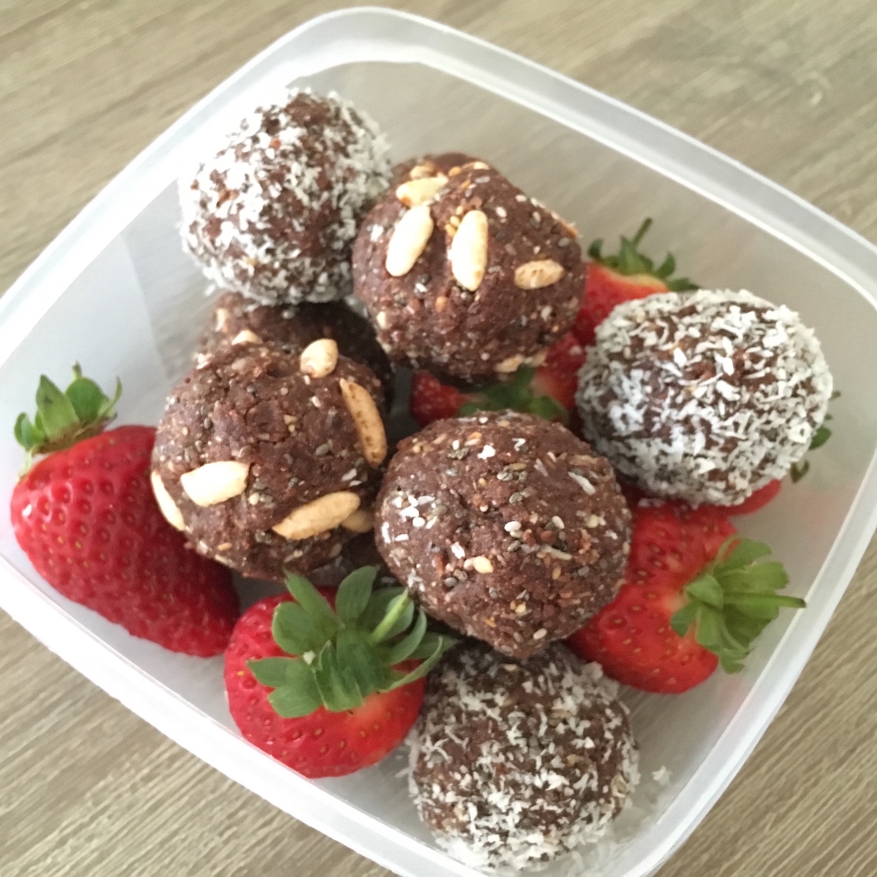Choc vanilla bliss balls in a container with strawberries