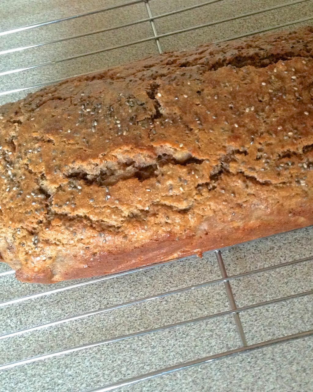 A loaf of banana walnut bread cooling on a wire rack