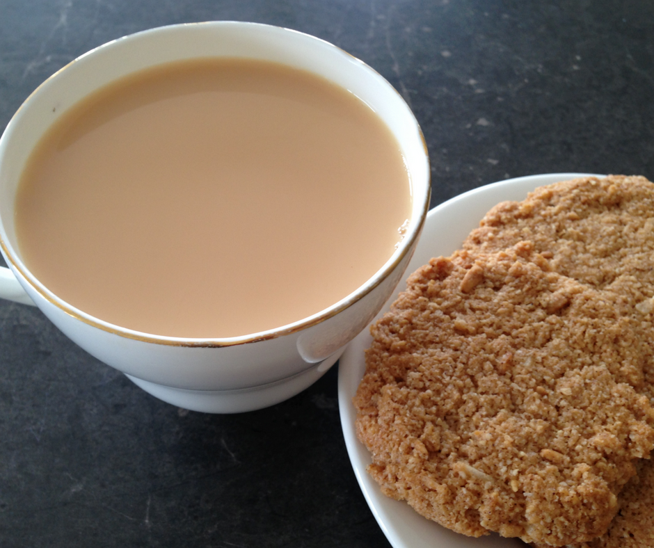 Anzac bickies on a plate with a cup of tea