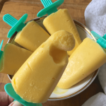 Mango ice cream pops in a bowl on a chopping board