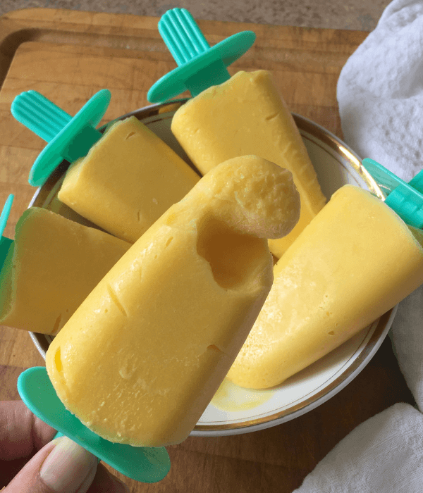 Mango ice cream pops in a bowl on a chopping board