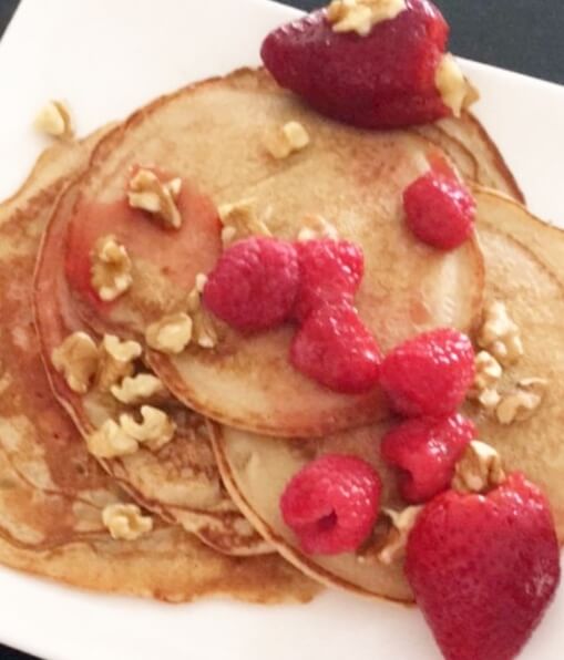 close up of pancakes topped with berries and walnuts