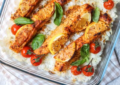 salmon and tomato tray bake on a bed of rice
