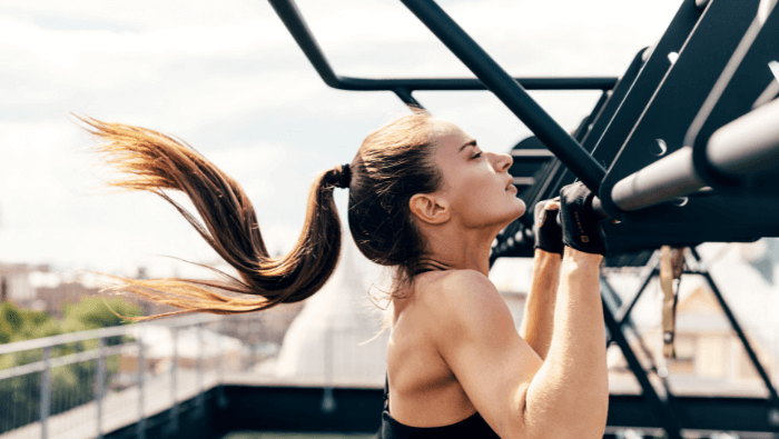 Woman doing a pull-up on outdoor equipment