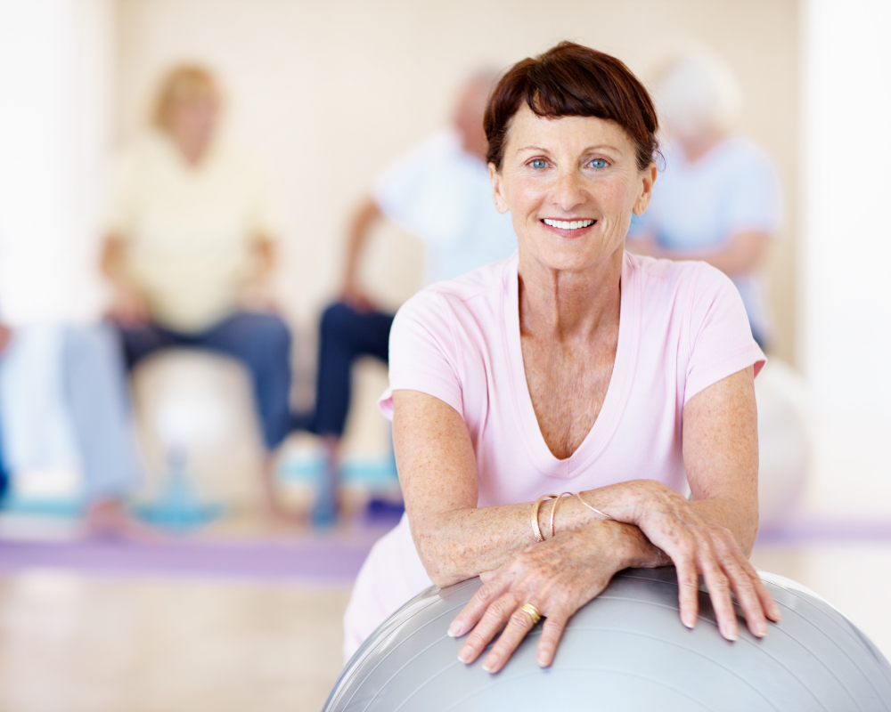 A fit and healthy older woman leaning on a fit ball