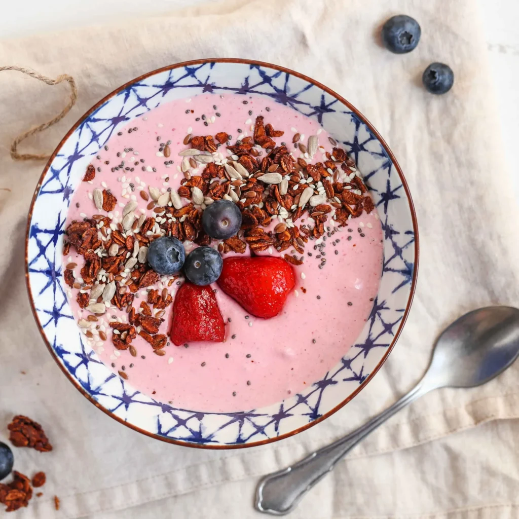 Strawberry smoothie bowl topped with berries, nuts and seeds